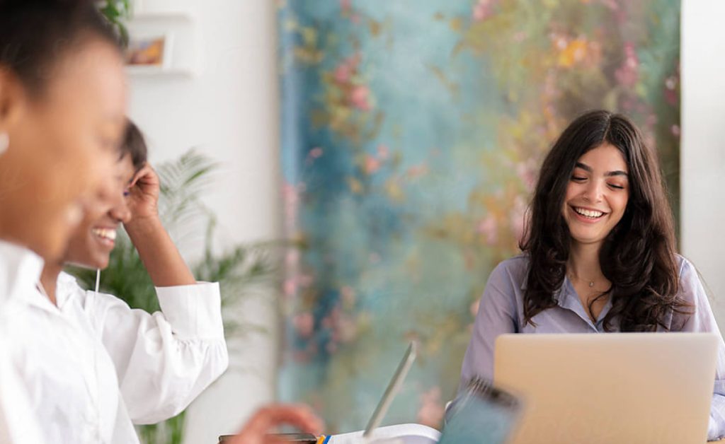 Get to know JobScore Three women sitting around a desk working with their laptops